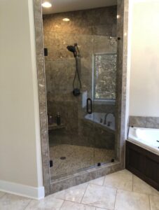 Frameless glass shower door in a modern bathroom with clean lines and custom tilework.