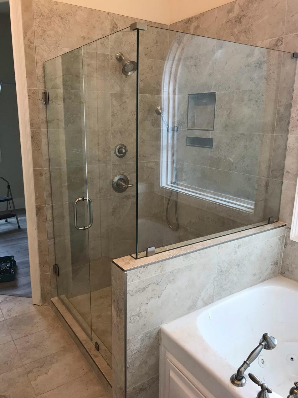 Hinged frameless glass shower door installed in a modern bathroom.