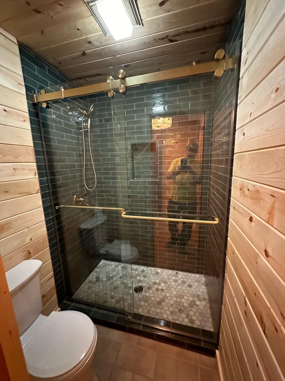 Sliding frameless glass shower door installed in a modern bathroom.